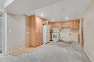 Kitchen with light brown cabinets, white appliances, concrete floors, light countertops, and recessed lighting