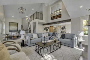 Living room featuring a high ceiling, recessed lighting, stairway, wood finished floors, and a chandelier
