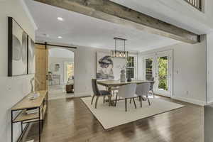 Dining space with a barn door, ornamental molding, arched walkways, recessed lighting, and light wood finished floors