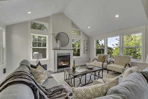 Living room with a high end fireplace, recessed lighting, and high vaulted ceiling