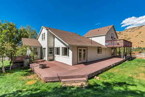 Back of house featuring a deck, french doors, roof with shingles, and a lawn