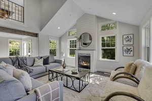 Living area featuring a glass covered fireplace, wood finished floors, recessed lighting, and high vaulted ceiling
