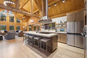 Kitchen with high vaulted ceiling, appliances with stainless steel finishes, a wood ceiling with exposed beams, a breakfast bar, and open shelves