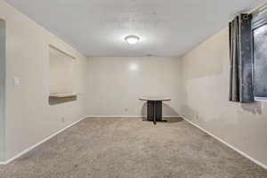 Carpeted spare room featuring a textured ceiling and baseboards