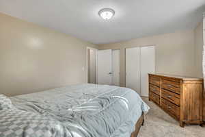 Bedroom with carpet floors, two closets, and a textured ceiling