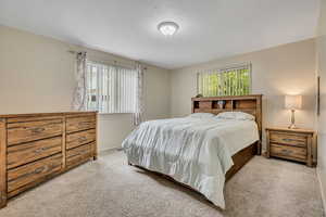 Bedroom with light colored carpet and a textured ceiling