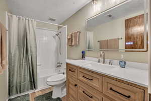 Bathroom with shower / bath combo, vanity, a textured ceiling, and light wood-style floors