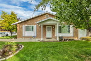Bungalow-style house with a porch, brick siding, and a front yard