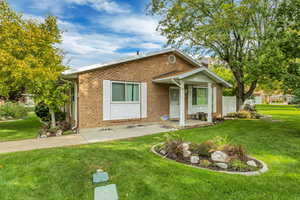View of front of property with brick siding, a front yard, and a patio