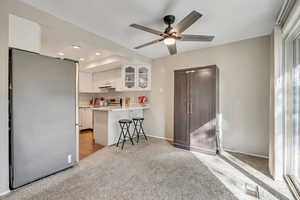 Kitchen with white cabinets, appliances with stainless steel finishes, glass insert cabinets, a breakfast bar, and light countertops