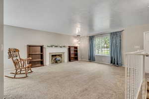 Living area with carpet, a textured ceiling, and a fireplace with flush hearth