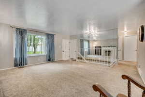 Empty room featuring carpet flooring, a textured ceiling, and a chandelier
