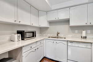 Kitchen featuring dishwasher, white cabinetry, stainless steel microwave, and dark wood finished floors