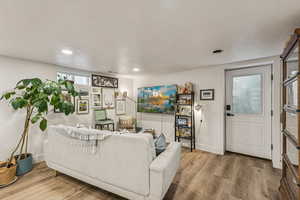 Living area with a textured ceiling, light wood finished floors, and recessed lighting
