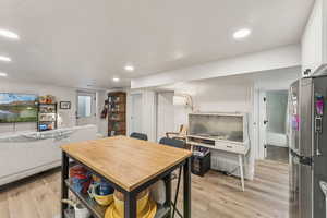 Dining area with light wood-style flooring, a textured ceiling, and recessed lighting
