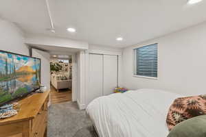 Carpeted bedroom with recessed lighting and a closet