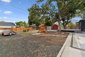 Fenced backyard featuring a playground and a shed