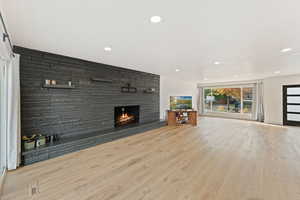 Unfurnished living room with a fireplace, wood finished floors, recessed lighting, and an accent wall