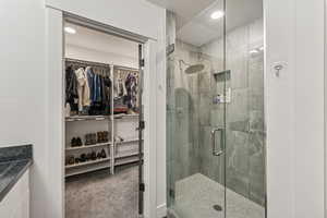 Full bathroom with a walk in closet, a stall shower, vanity, and a textured ceiling