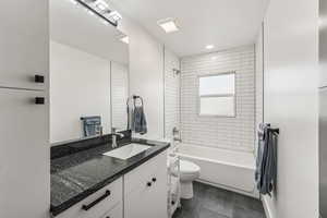 Bathroom with shower / washtub combination, vanity, dark tile patterned floors, and recessed lighting