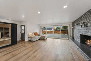 Living area with light wood-style floors, recessed lighting, a stone fireplace, and a textured ceiling