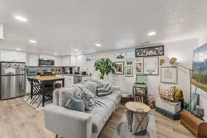 Living room featuring light wood-style flooring, a textured ceiling, and recessed lighting