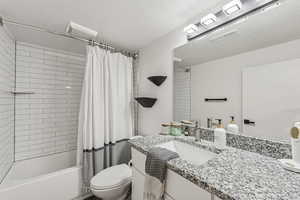 Bathroom featuring shower / tub combo, vanity, and a textured ceiling