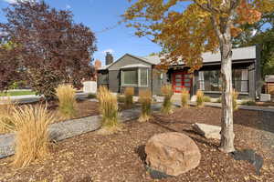 View of front facade featuring brick siding, a chimney, and french doors
