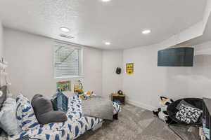 Carpeted bedroom with a textured ceiling and recessed lighting