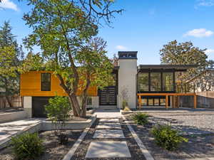 Contemporary house featuring concrete driveway, a garage, a chimney, and a patio