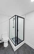 Full bathroom featuring a stall shower and dark tile patterned flooring