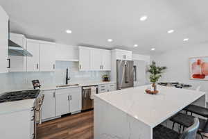 Kitchen featuring light stone counters, a kitchen island, high quality appliances, white cabinetry, and recessed lighting