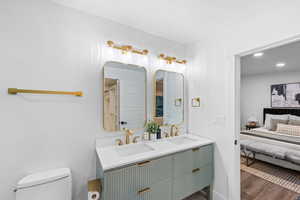 Ensuite bathroom with double vanity, dark wood finished floors, and recessed lighting