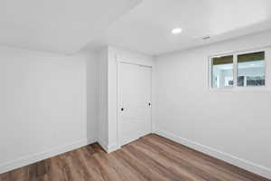 Unfurnished bedroom with a closet, wood finished floors, and recessed lighting