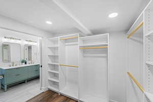 Spacious closet with dark wood-style flooring and a sink