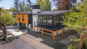 Back of property with a metal roof, a standing seam roof, and a sunroom