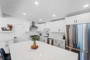 Kitchen featuring high quality appliances, white cabinets, backsplash, light stone counters, and recessed lighting