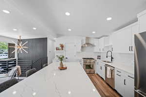 Kitchen featuring light stone countertops, recessed lighting, white cabinetry, stainless steel appliances, and backsplash