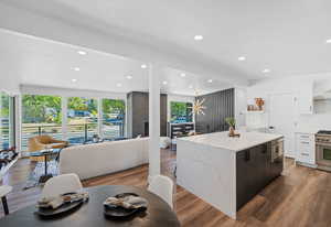 Kitchen with light stone countertops, dark wood-style flooring, a center island, recessed lighting, and stainless steel appliances