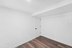 Spare room with baseboards and dark wood-type flooring