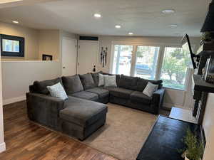 Living area with recessed lighting, healthy amount of natural light, wood finished floors, and a textured ceiling