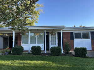 Ranch-style home with a porch, brick siding, and a front yard