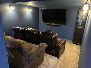 Carpeted home theater featuring a textured ceiling and baseboards