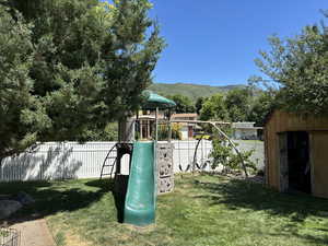 View of playground featuring a fenced backyard, a storage shed, and a mountain view
