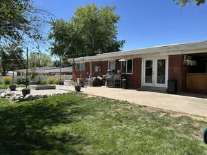 Back of house featuring french doors, brick siding, and a patio area