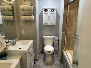 Bathroom with vanity, tiled shower / bath combo, and dark tile patterned flooring
