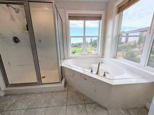 Full bathroom featuring a garden tub, a marble finish shower, and light tile patterned flooring