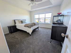 Bedroom featuring carpet floors, a tray ceiling, and ceiling fan