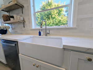 Kitchen featuring dishwasher, tasteful backsplash, open shelves, light stone counters, and gray cabinets
