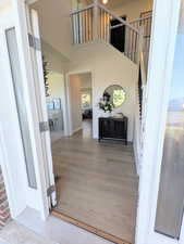 Entryway with light wood-style floors, a high ceiling, and stairway
